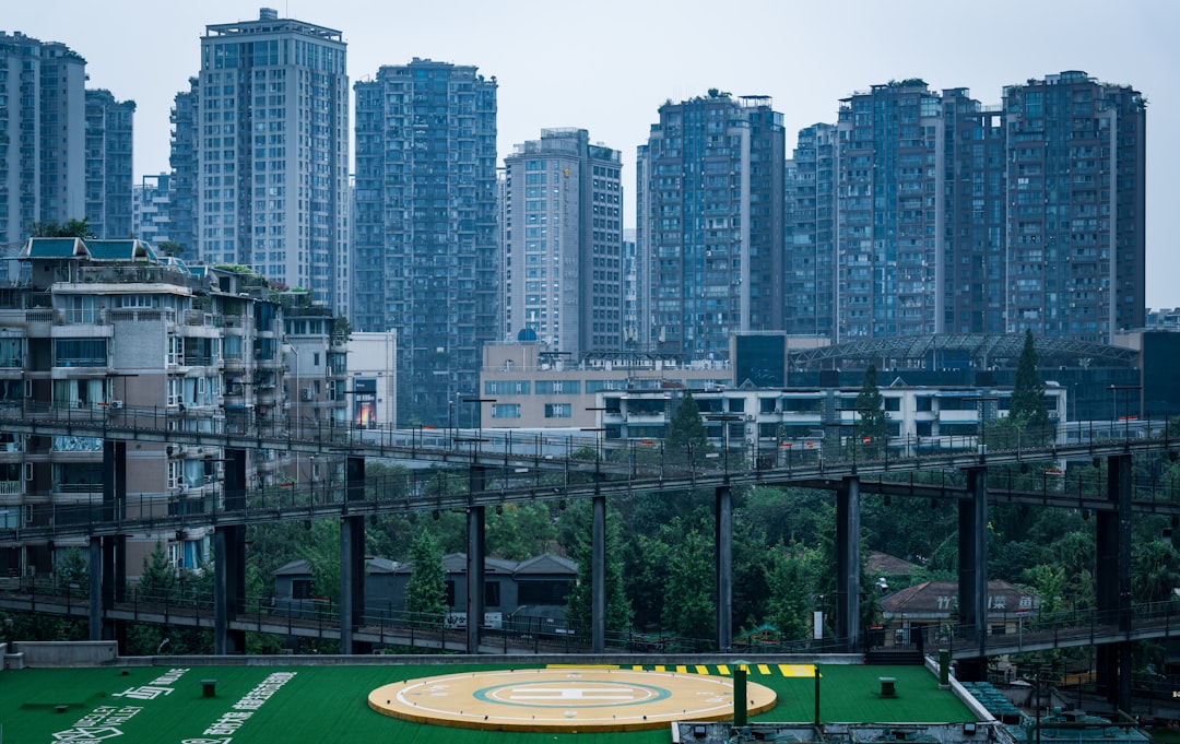 Tall apartment buildings overlook a green area with structures.